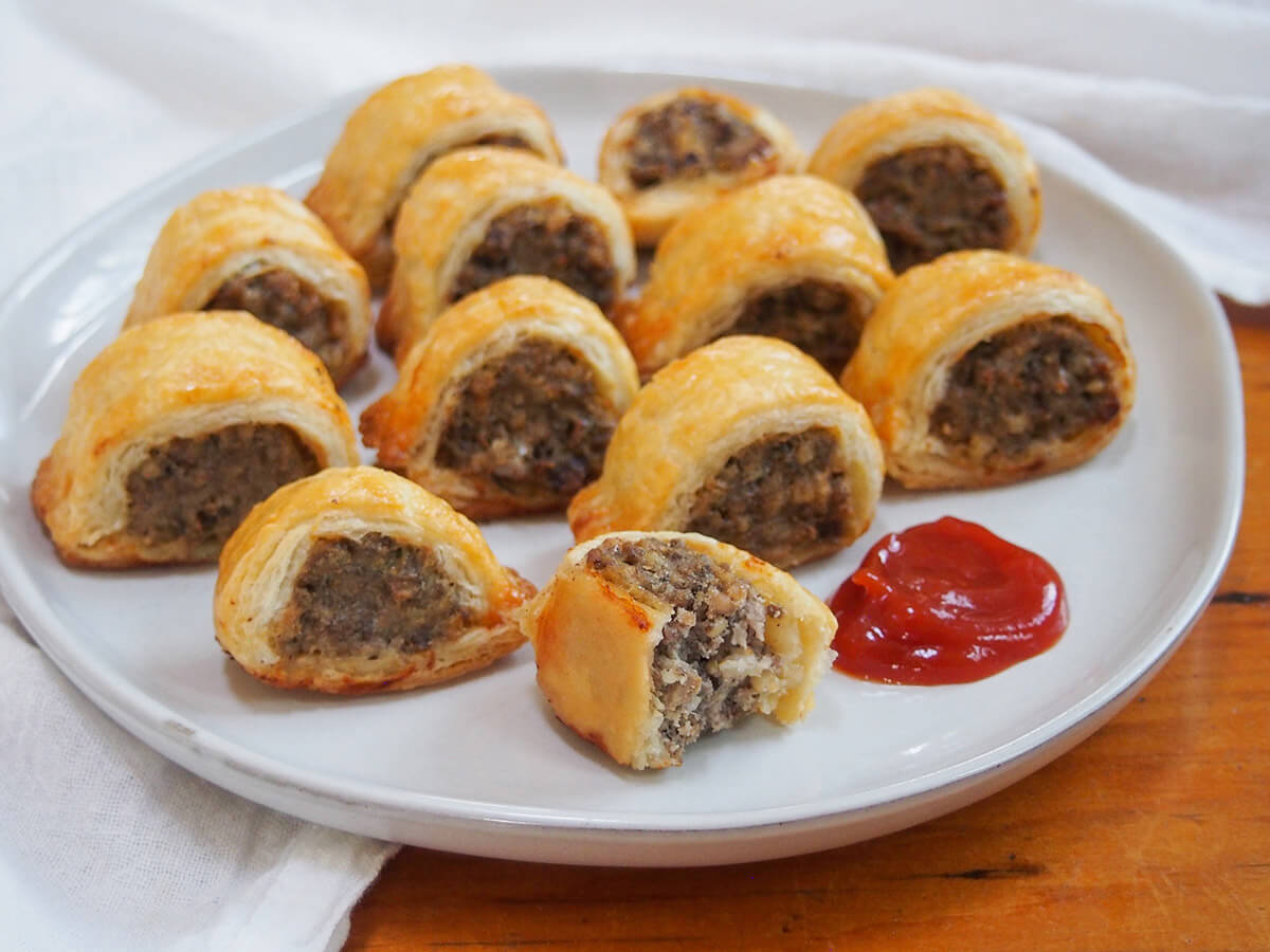 plate with haggis sausage rolls with one bitten one at front and ketchup to side