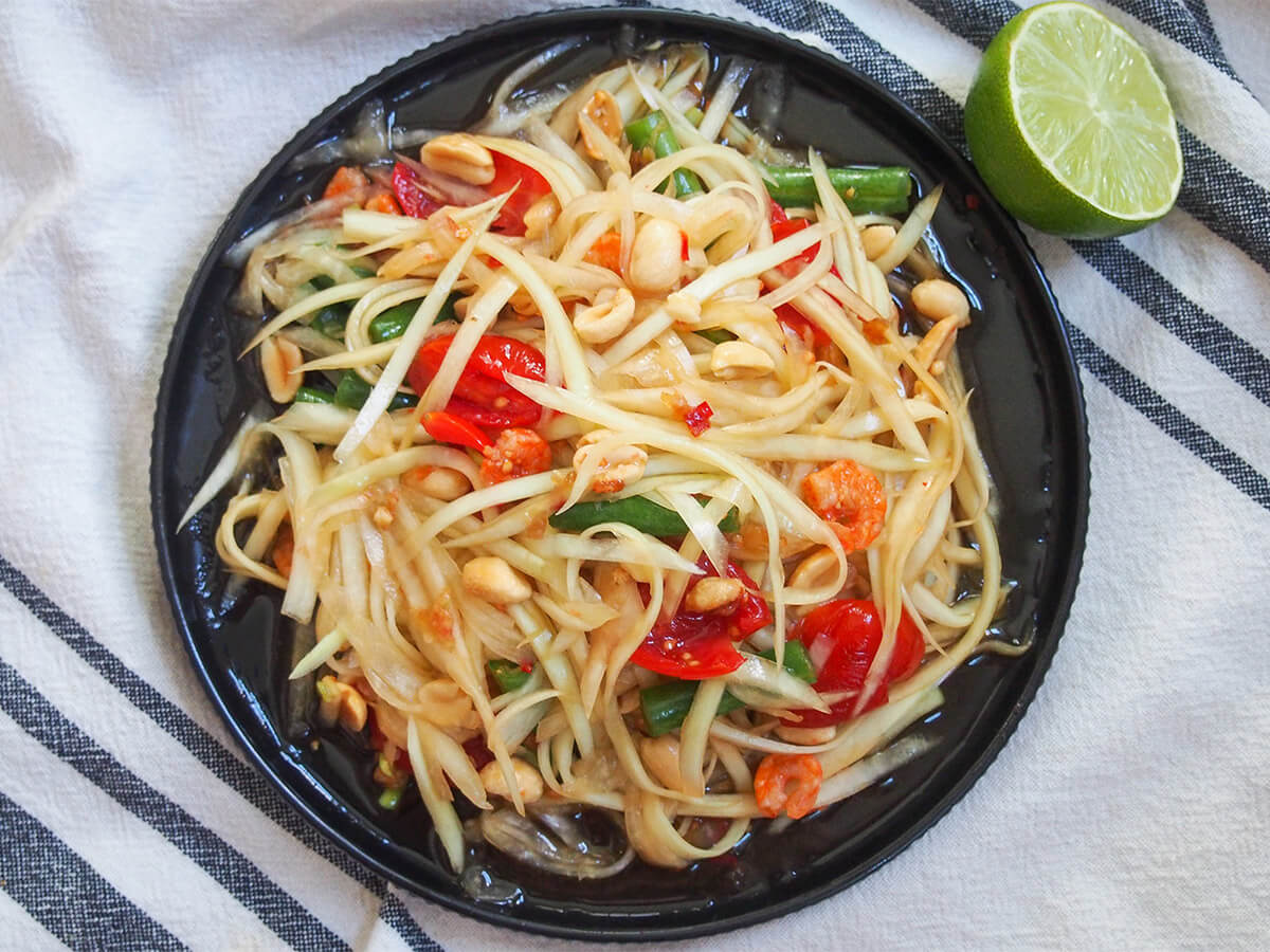 Thai green papaya salad overhead view of Thai green papaya salad with half lime to side