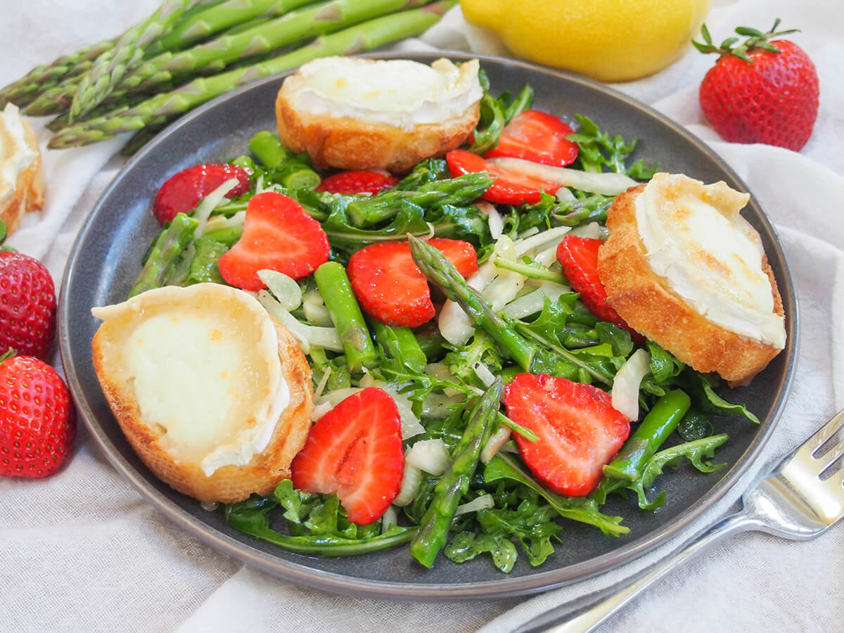 plate of strawberry asparagus salad with goat cheese toasts around plate