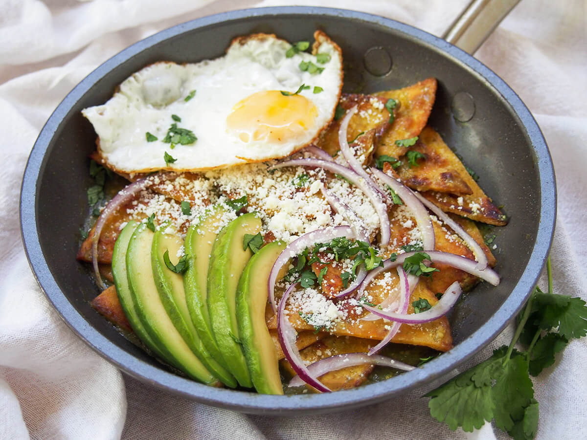 chilaquiles verdes topped with avocado and fried egg