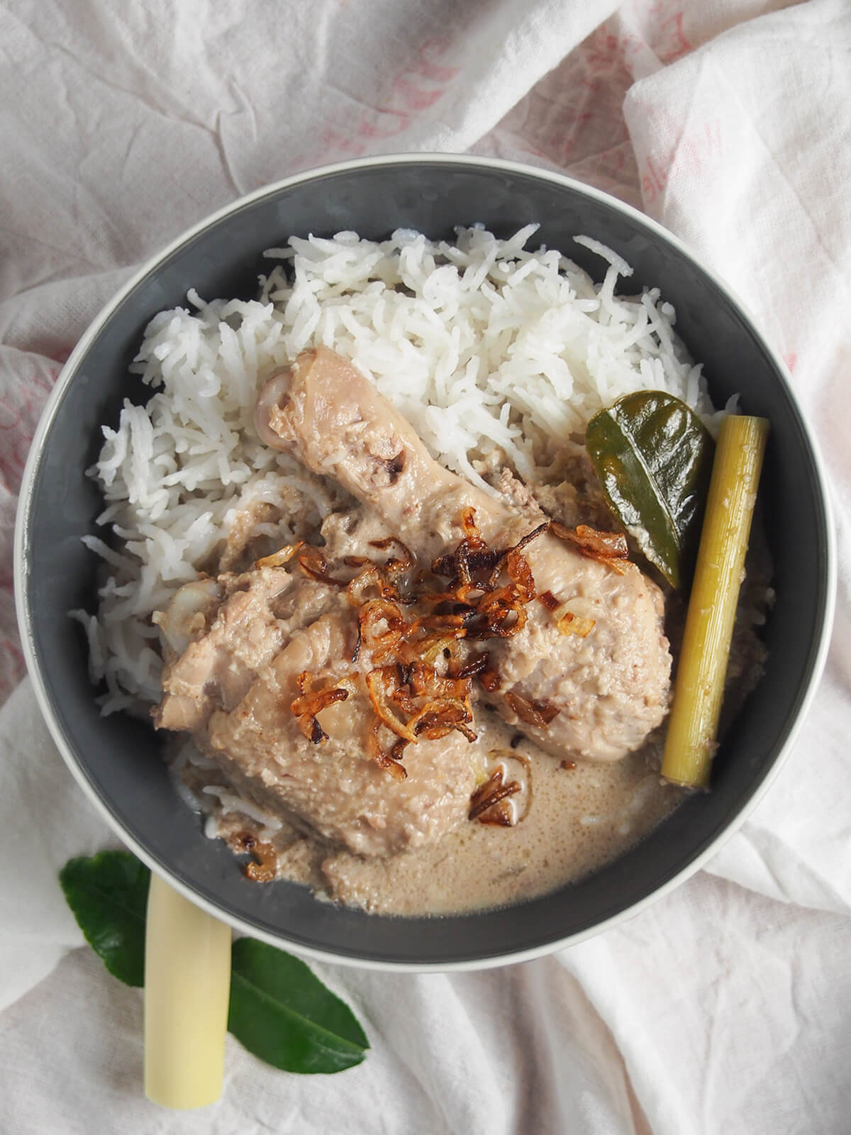 overhead view of a bowl of opor ayam Indonesian coconut chicken with rice.