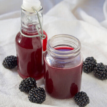 bottle and jar of blackberry simple syrup next to each other.
