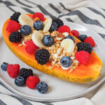 side view of a papaya boat loaded with berries and granola.