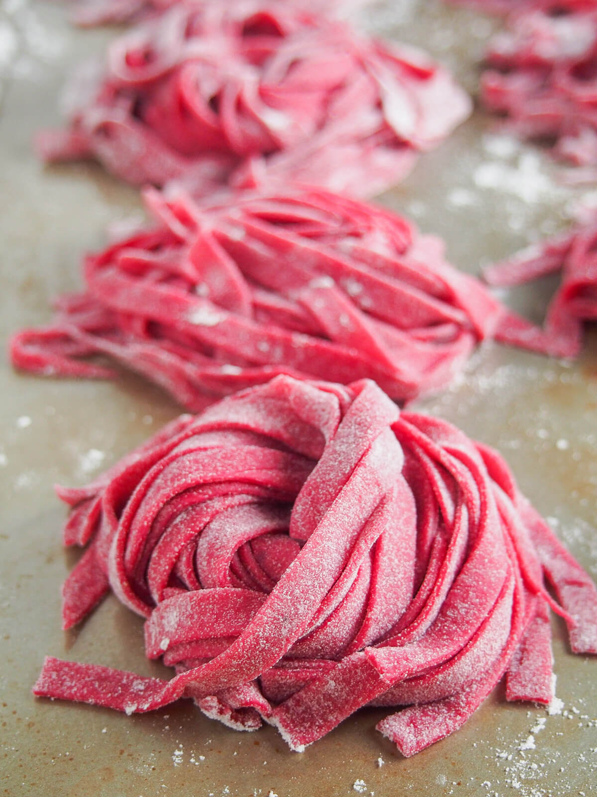 This beet pasta dough (beetroot pasta dough) creates a beautiful pink pasta thanks to beet puree. It's colorful, with a lovely soft texture and tastes delicious, too. stacks of linguini beet pasta dough.