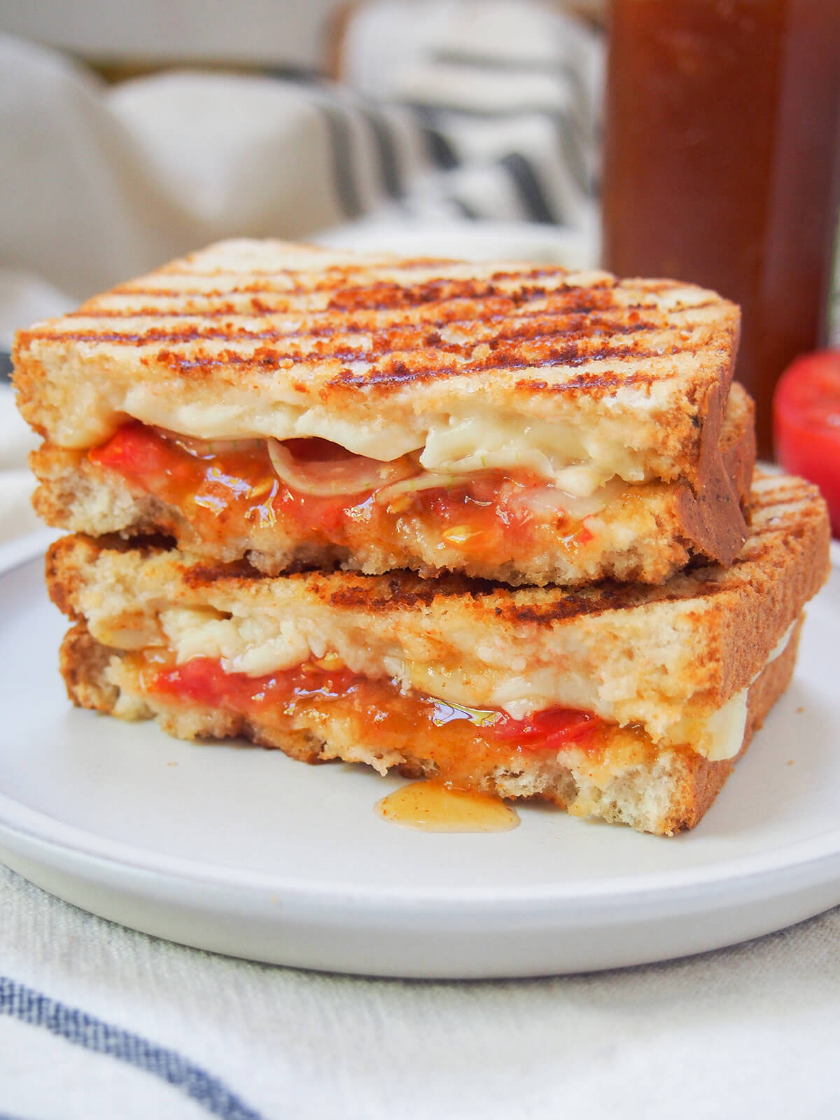 A braaibroodjie is a South African grilled cheese sandwich, made extra delicious with chutney and more inside. They are easy to make and so delicious. Traditionally, you cook over the barbecue/grill but you can also use a grill pan or panini press instead (even if it loses a little of that fire flavor). two halves of a braaibroodjie, S African grilled cheese, on a plate.