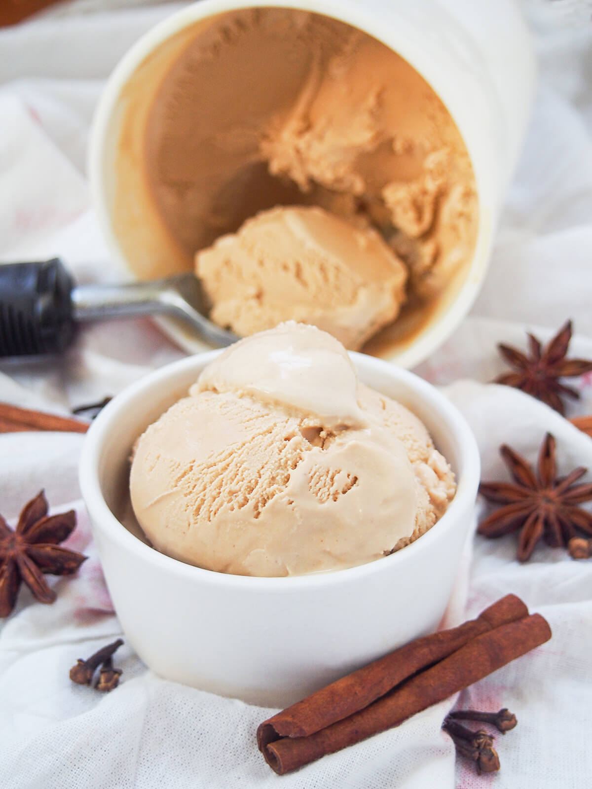 dish of chai ice cream with scoop in tub on side behind.