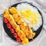 overhead view of plate of jujeh kabab, rice and tomatoes.