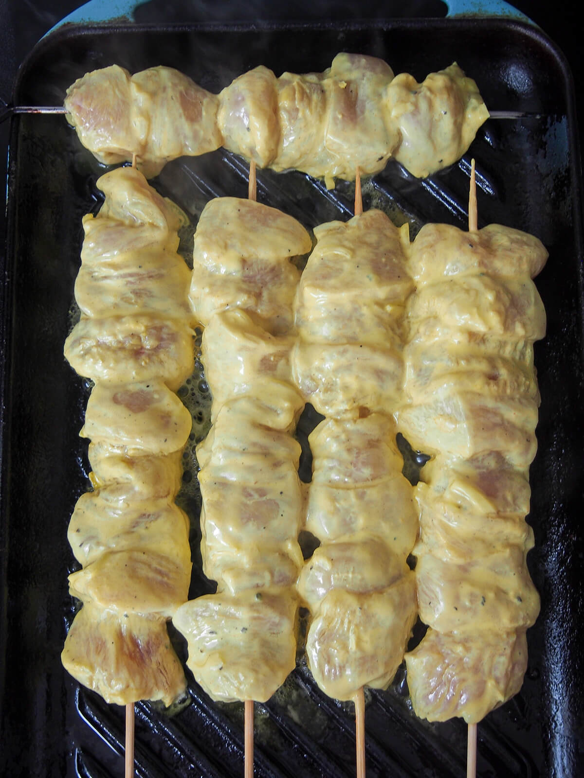 starting to cook skewers of joojeh kabab skewers starting to cook on grill.