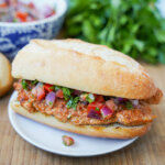 close up view of choripan, Argentine chorizo sandwich with salsa on top of chorizo.