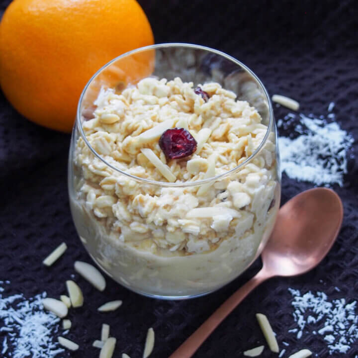 glass of orange overnight oats with spoon to side