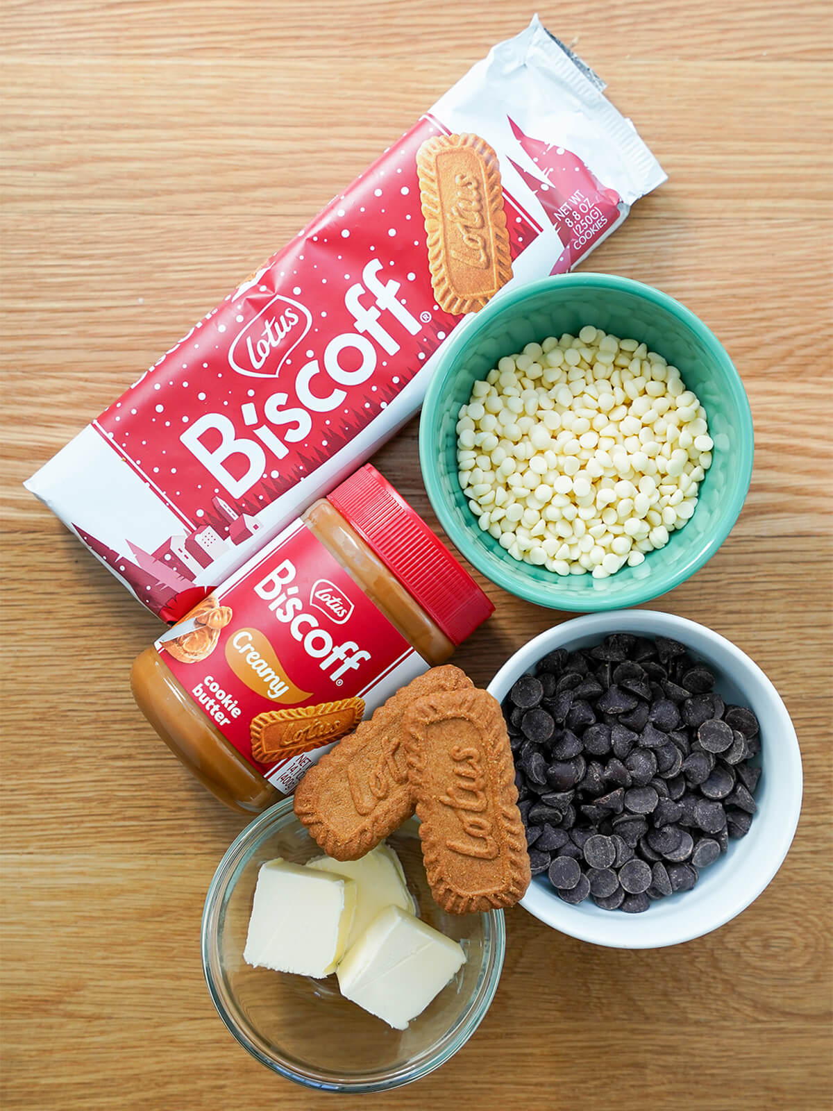 ingredients for biscoff truffles packed of biscoff cookies, jar of biscoff cookie butter, white and dark chocolate and dish with butter.