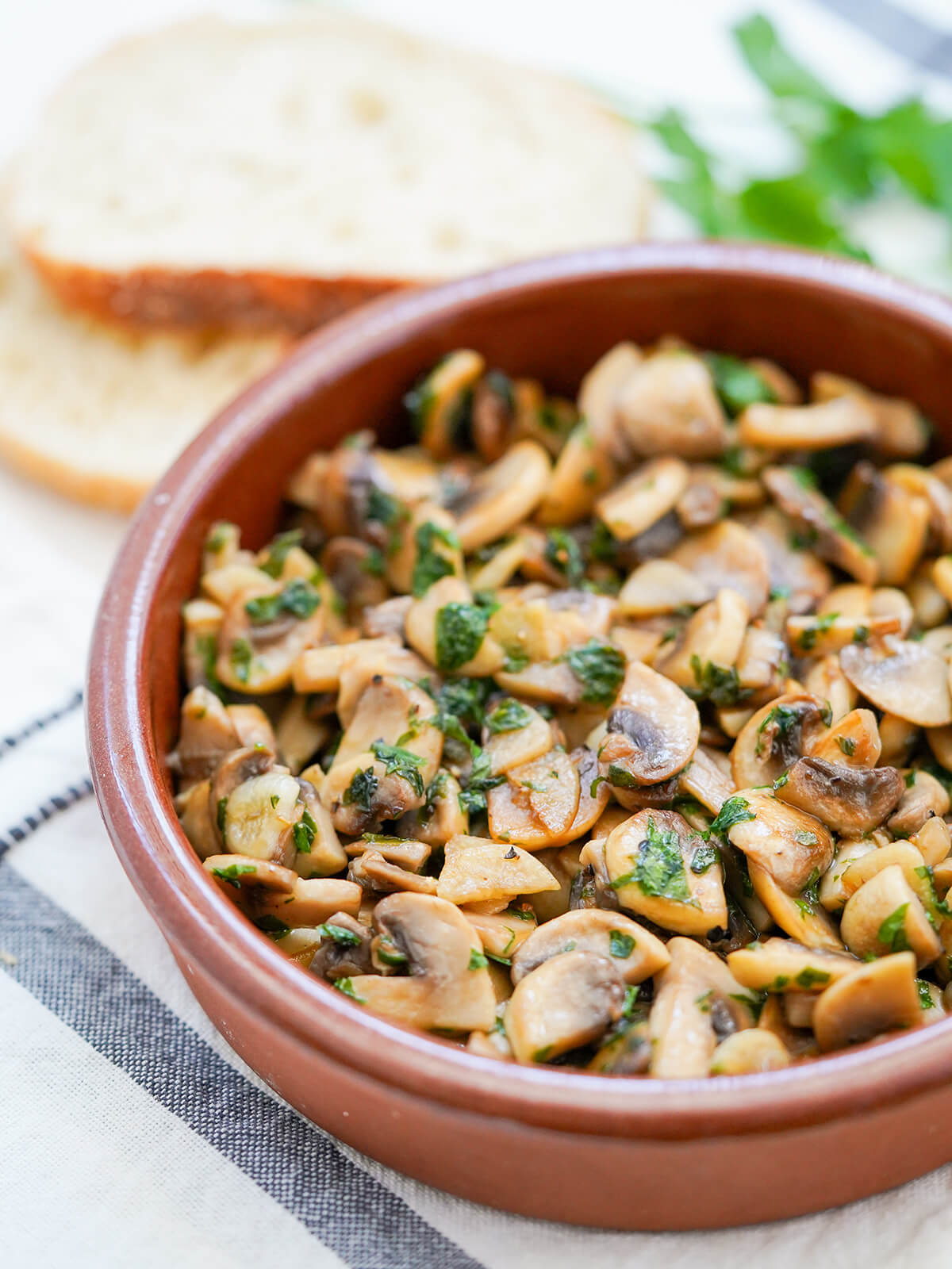 side view of dish of Spanish garlic mushrooms, champiñones al ajillo.