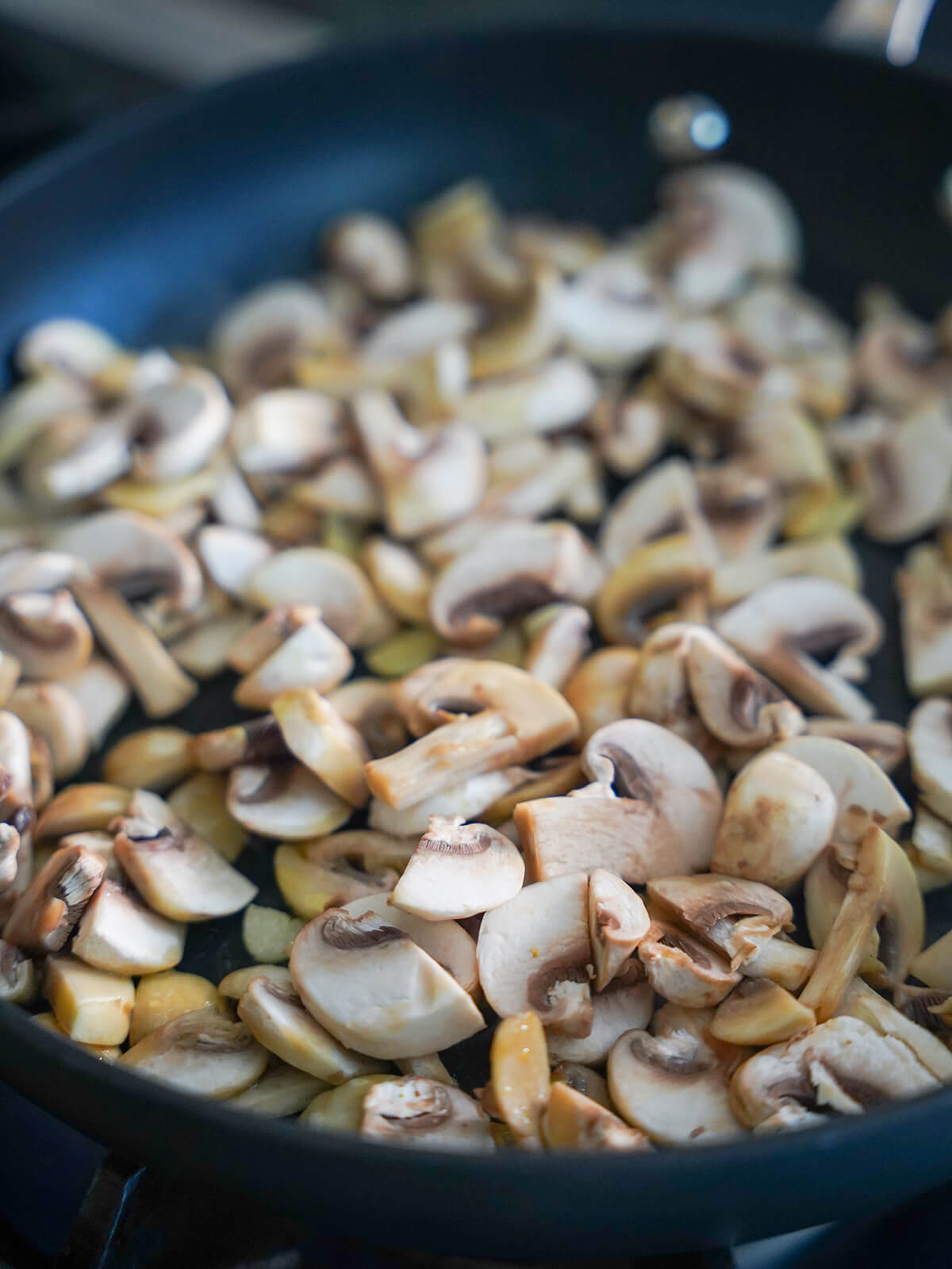 mushrooms cooking in skillet from side.