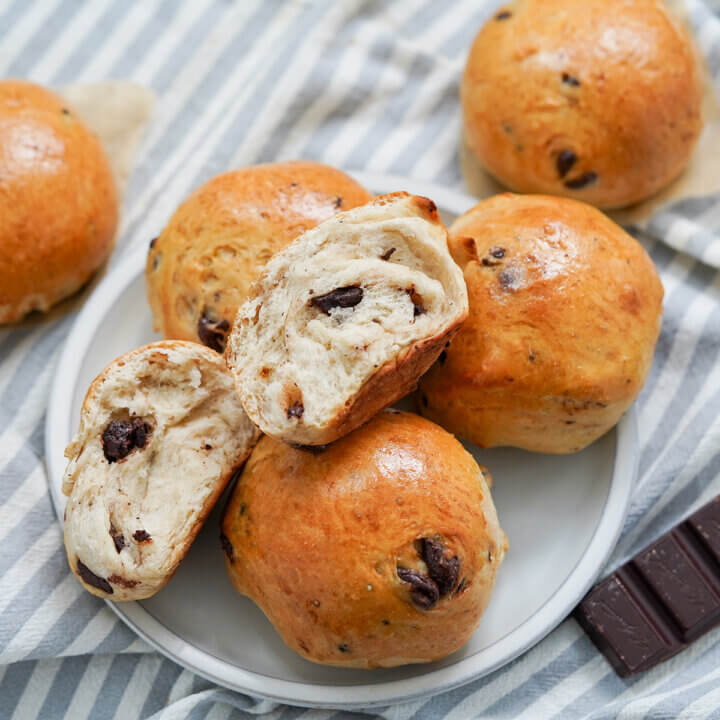 plate of Norwegian chocolate buns, sjokoladeboller with one split open showing chocolate chunks inside.