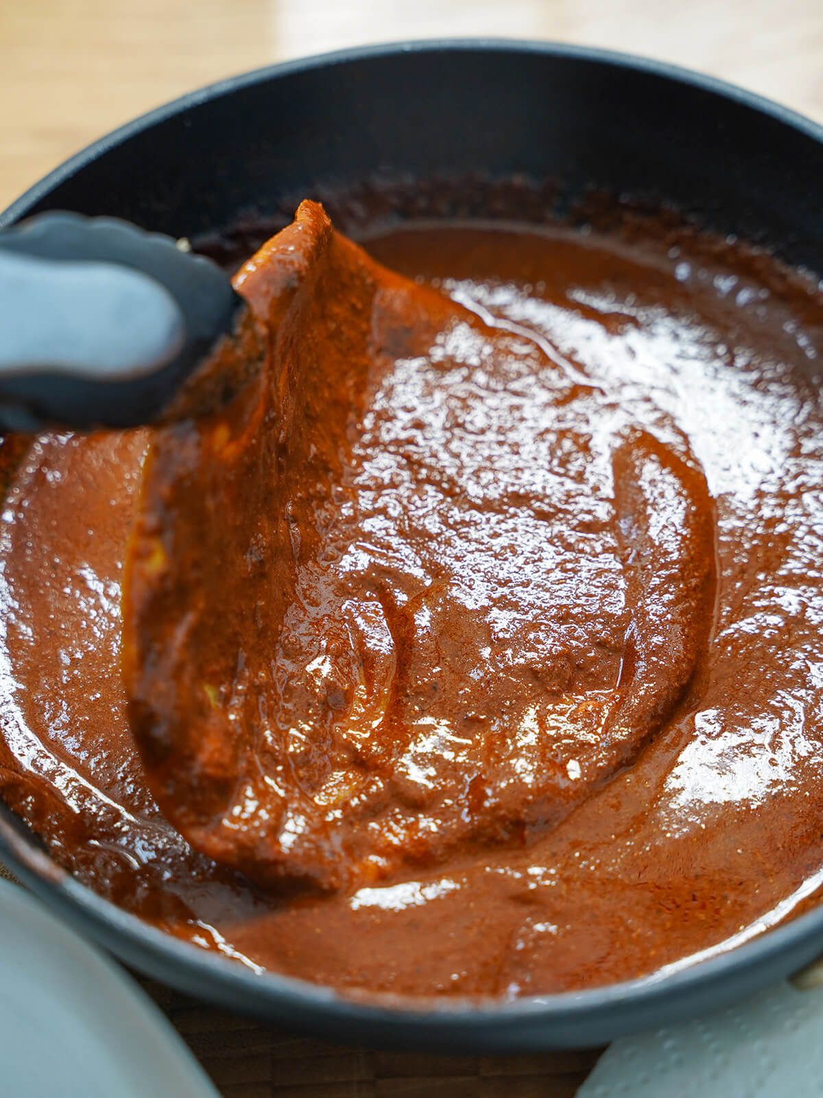 dipping a tortilla in mole sauce.
