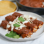 side view of three enmoladas on a plate.