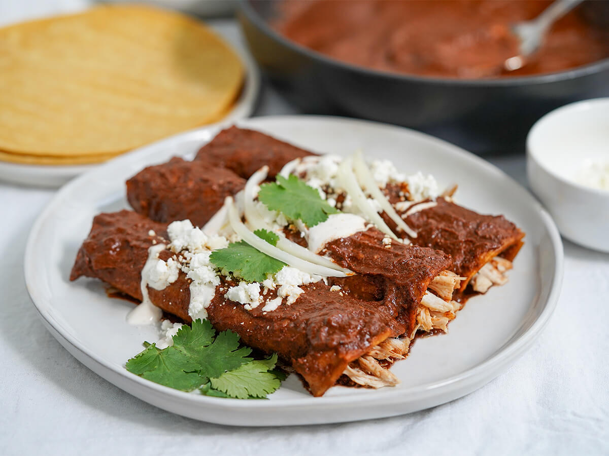 three chicken-filled enmoladas on a plate viewed from side.