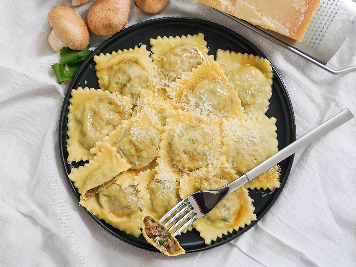 mushroom ravioli plate of mushroom ravioli with fork of part of a ravioli resting on top.