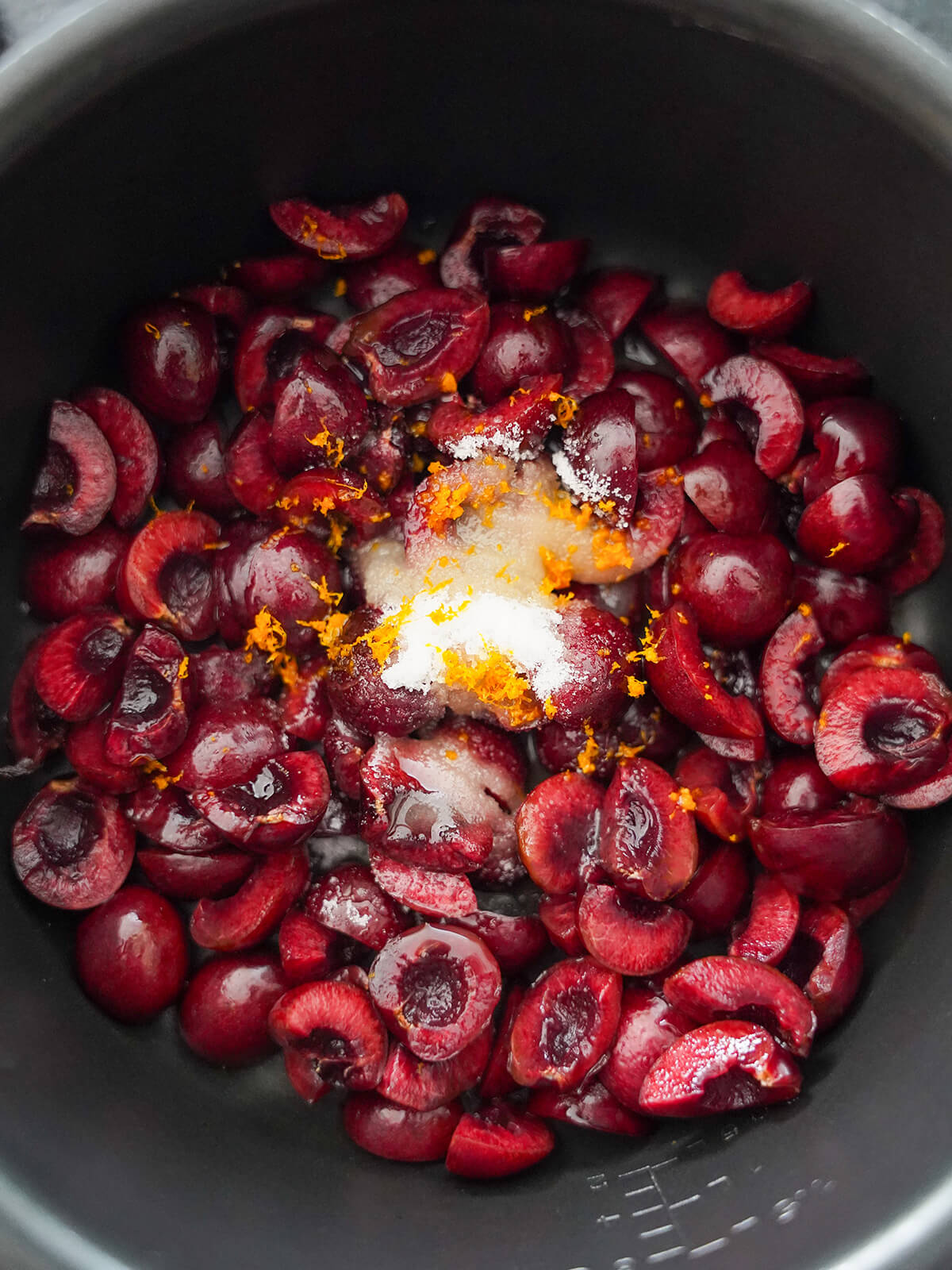 cherry compote ingredients before cooking chopped cherries with sugar and orange zest on top.