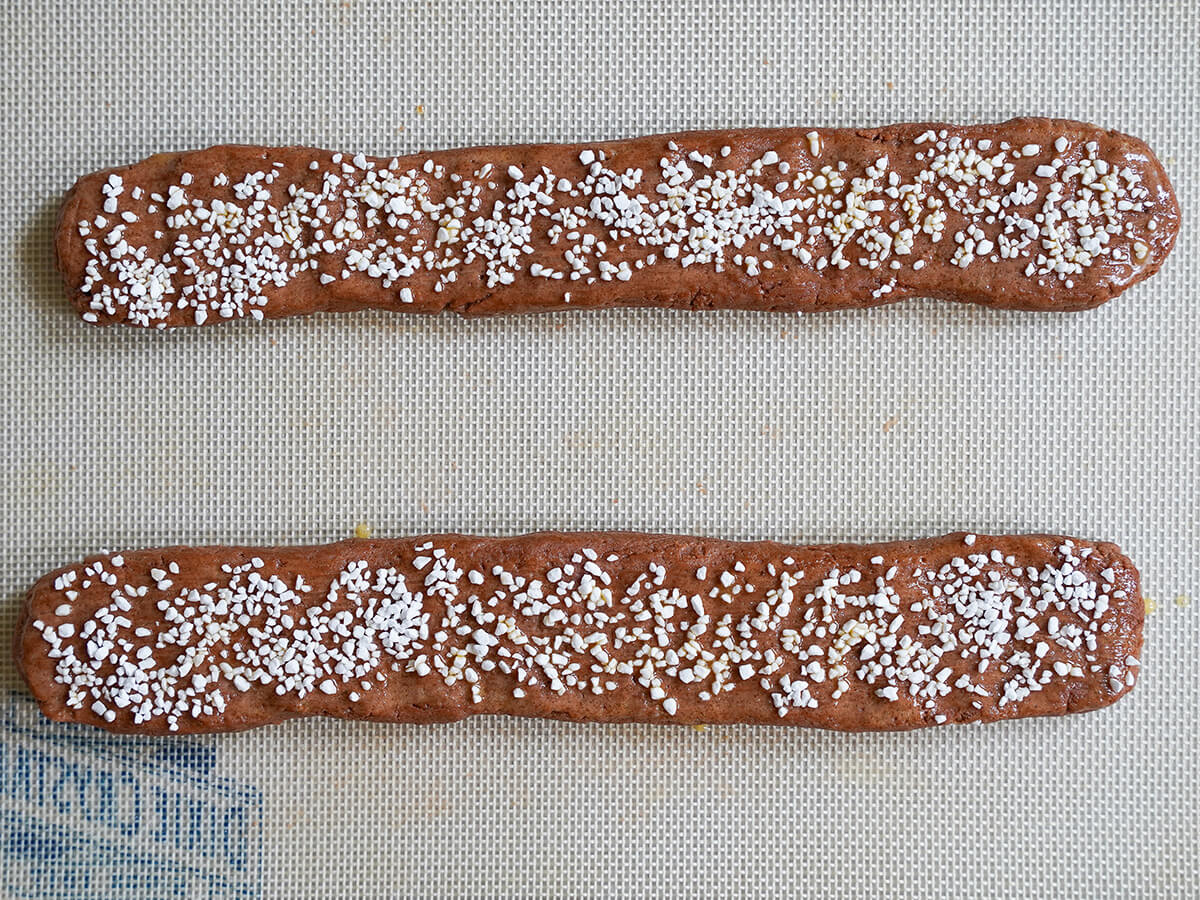 chokladsnittar, Swedish chocolate cookie slices, logs of mixture before baking. two logs of cookie mixture topped with pearl sugar sitting on silicone mat before baking.