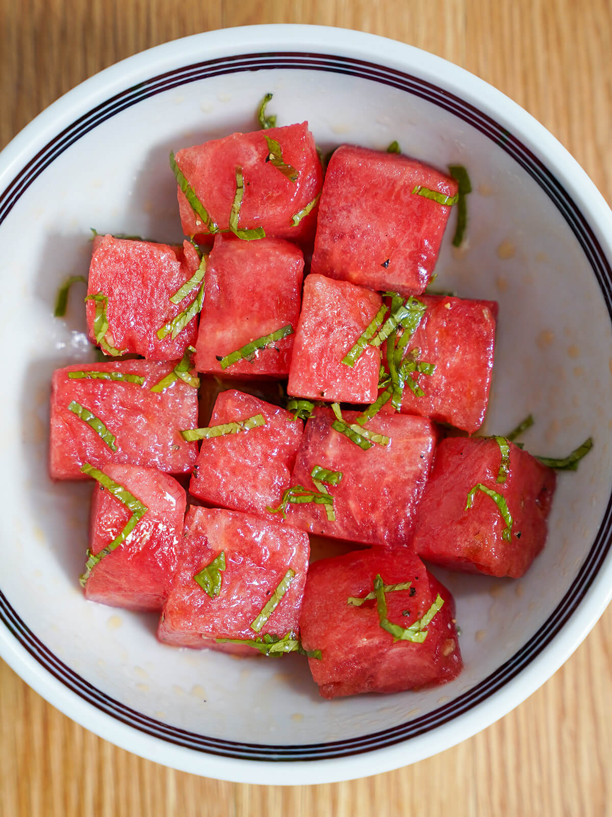 watermelon for halloumi and watermelon salad watermelon chunks in bowl with thinly sliced mint and dressing.