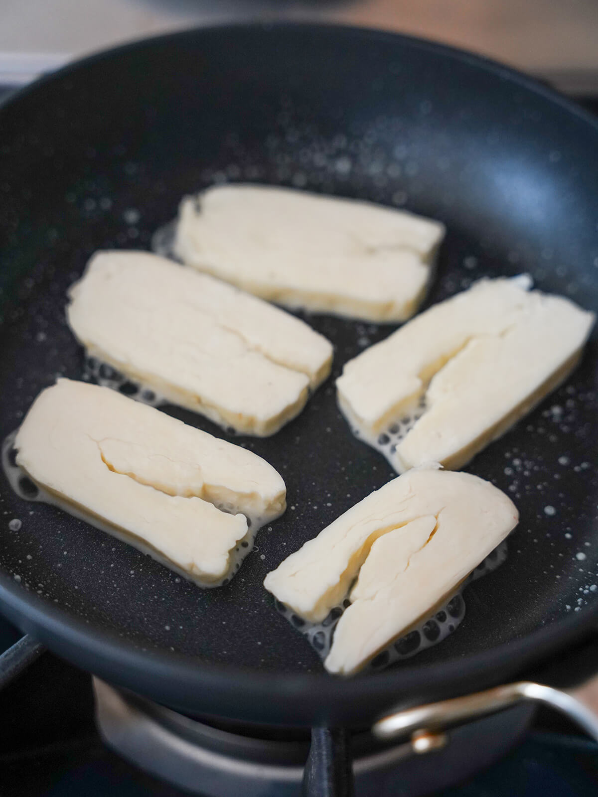 cooking halloumi for halloumi and watermelon salad slices of halloumi frying on skillet