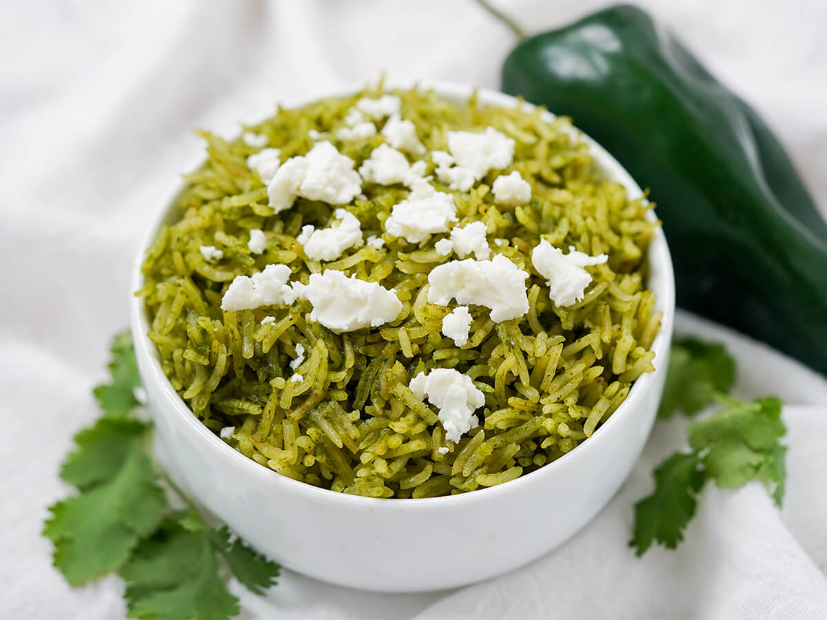 bowl of arroz verde, Mexican green rice bowl of arroz verde, Mexican green rice, with poblano pepper in background and cilantro either side of bowl.