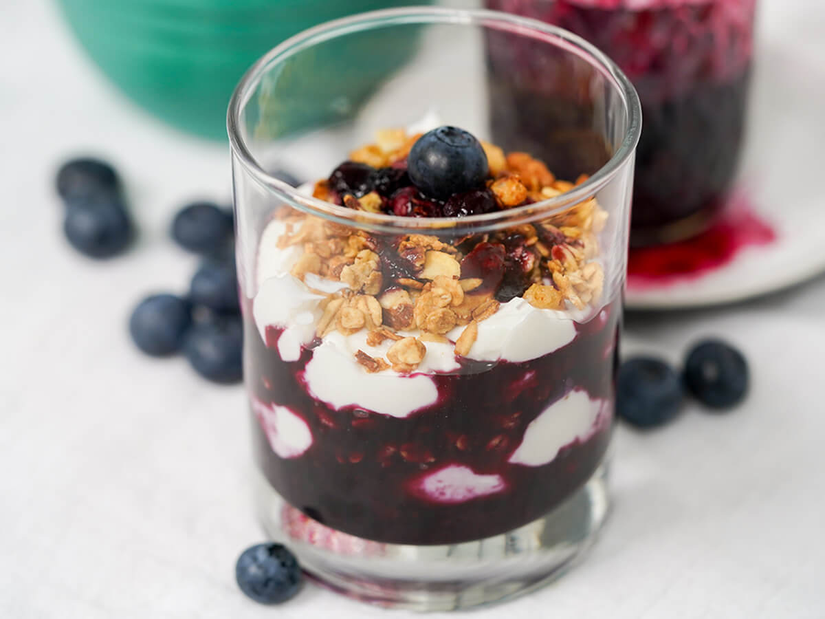 blueberry parfait side view of glass of blueberry parfait.