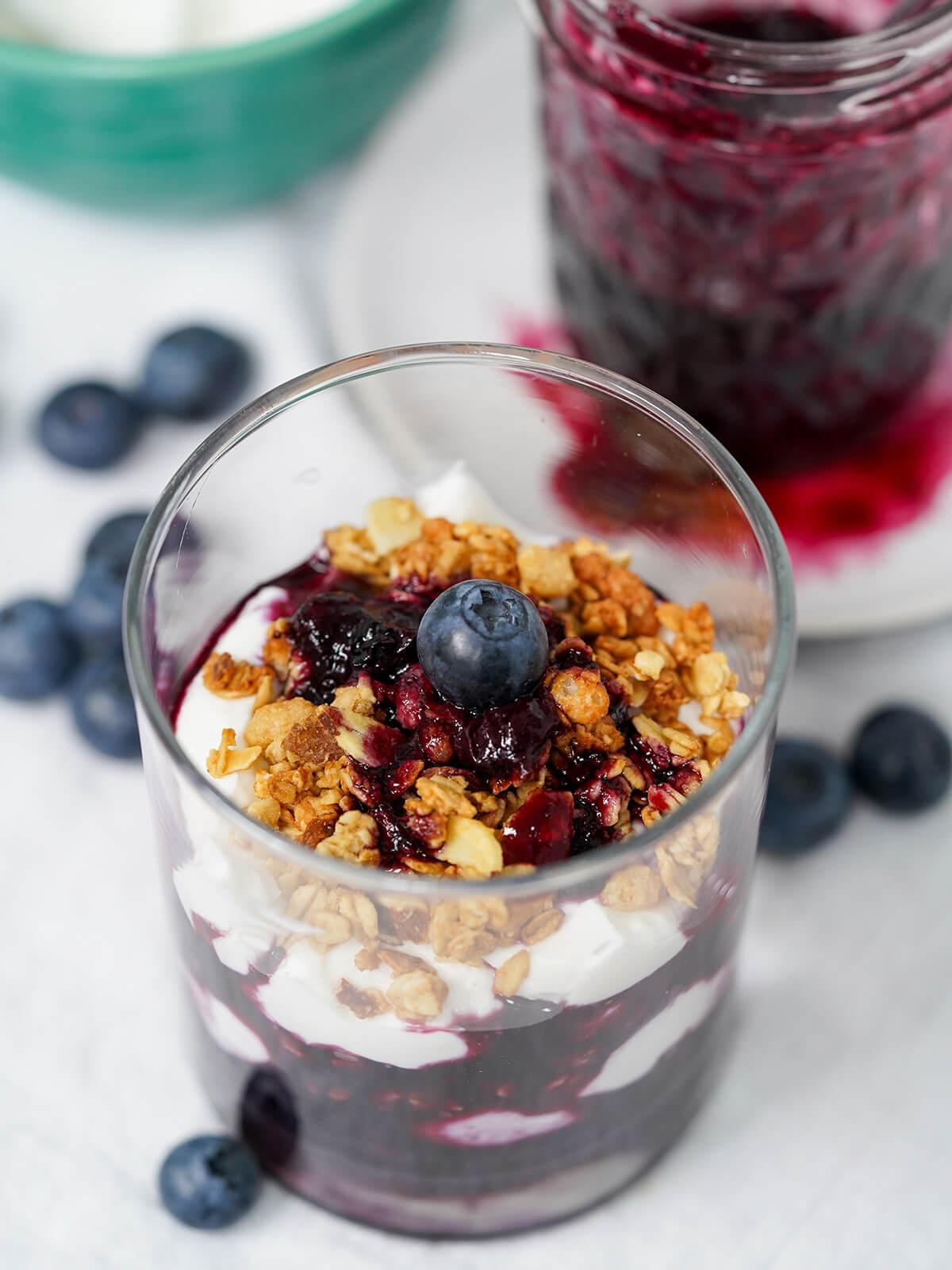 This blueberry parfait is a delicious combination of creamy yogurt, crunchy granola and luscious, fruity blueberry compote. So simple and quick to make, it's great for breakfast or a snack. view of blueberry parfait part overhead showing granola on top and layers of yogurt and blueberry.