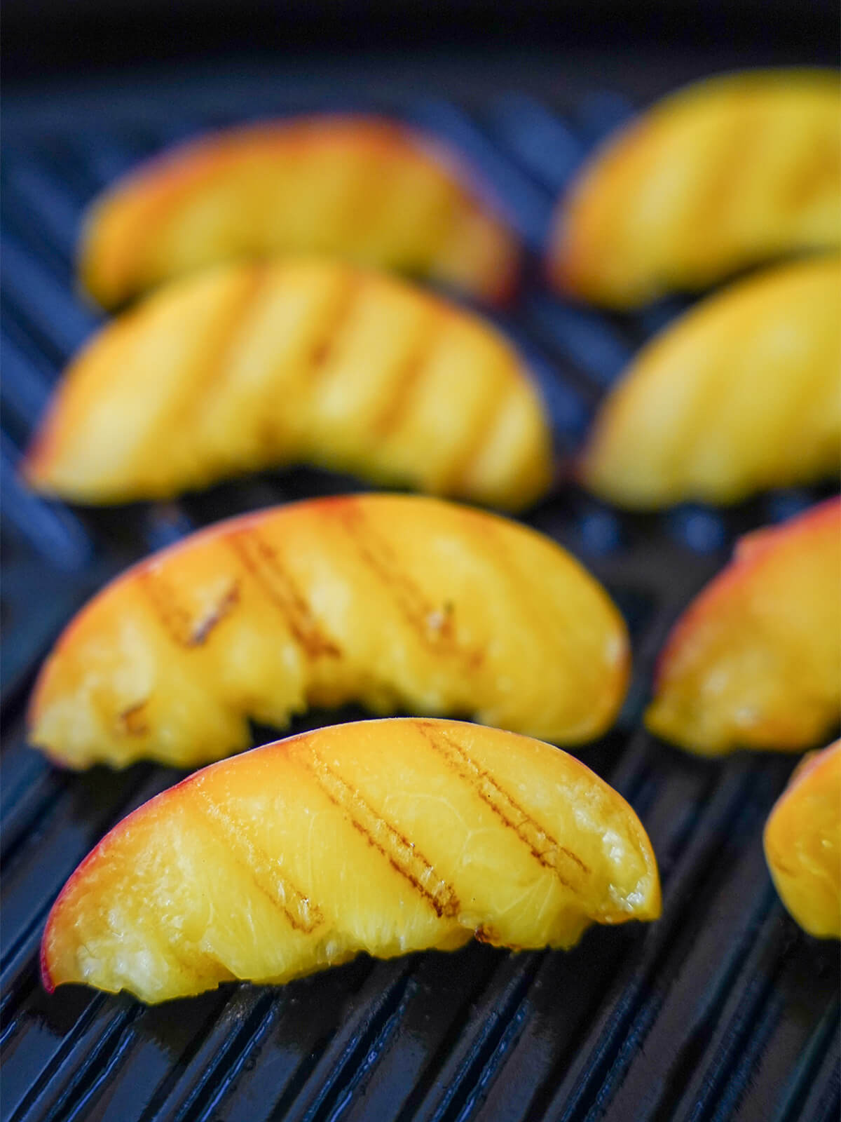 grilling slices of peach with grill marks showing on top of slices.
