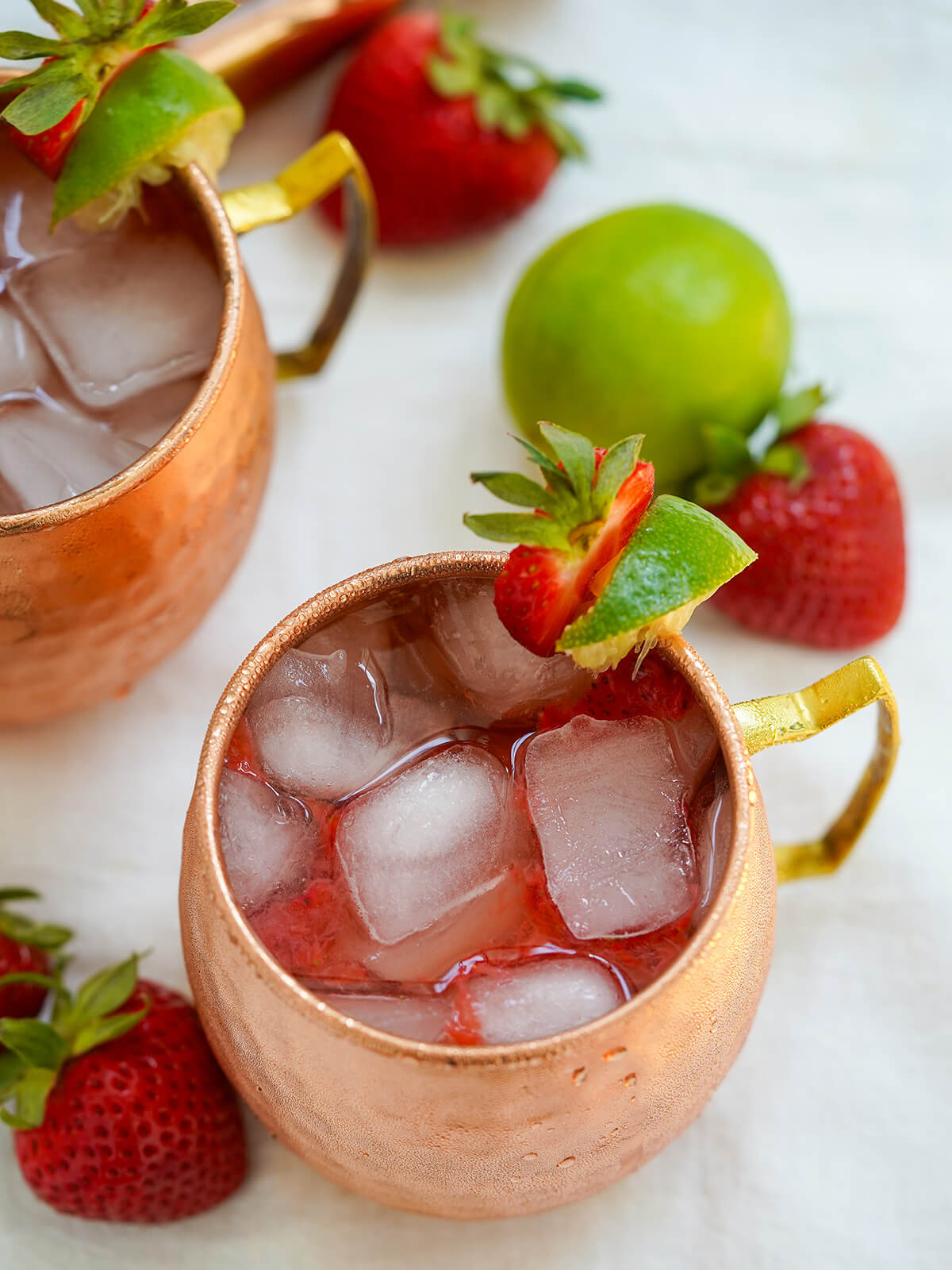 overhead of strawberry Moscow mule overhead view of mug of strawberry Moscow mule showing cubes of ice and strawberry and lime garnish.