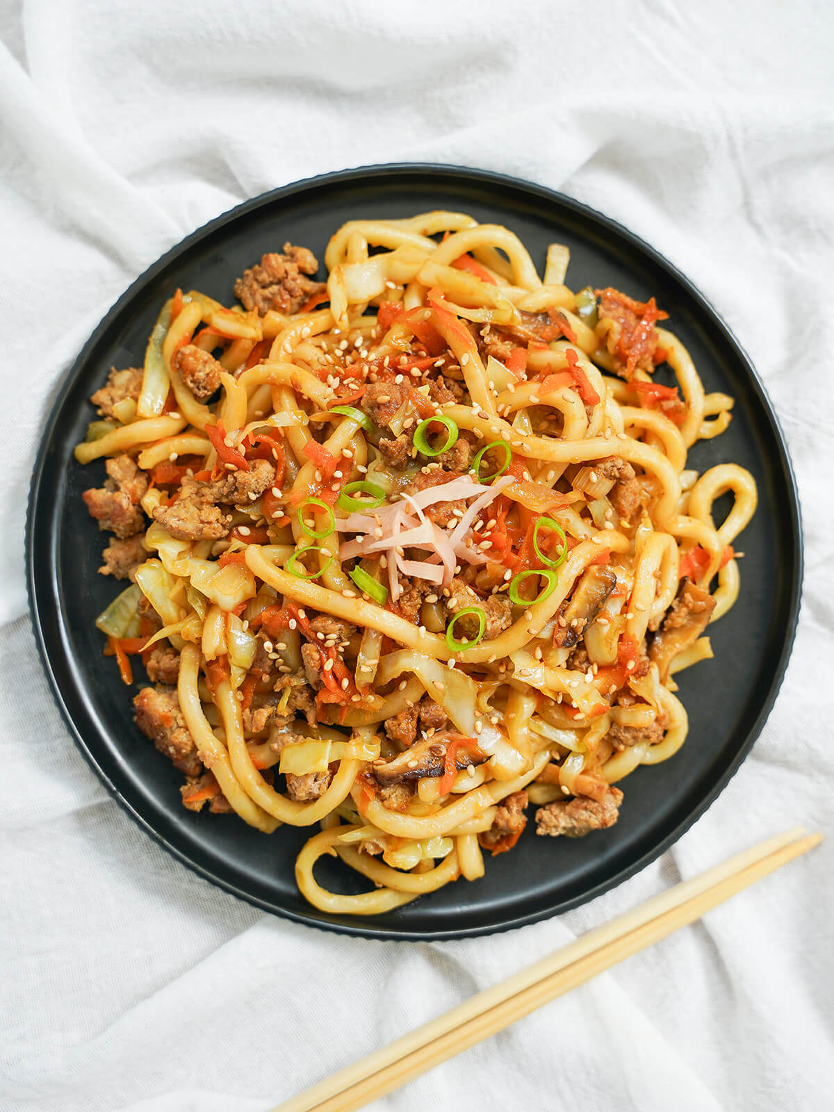 overhead view of plate of yaki udon with chopsticks below plate.