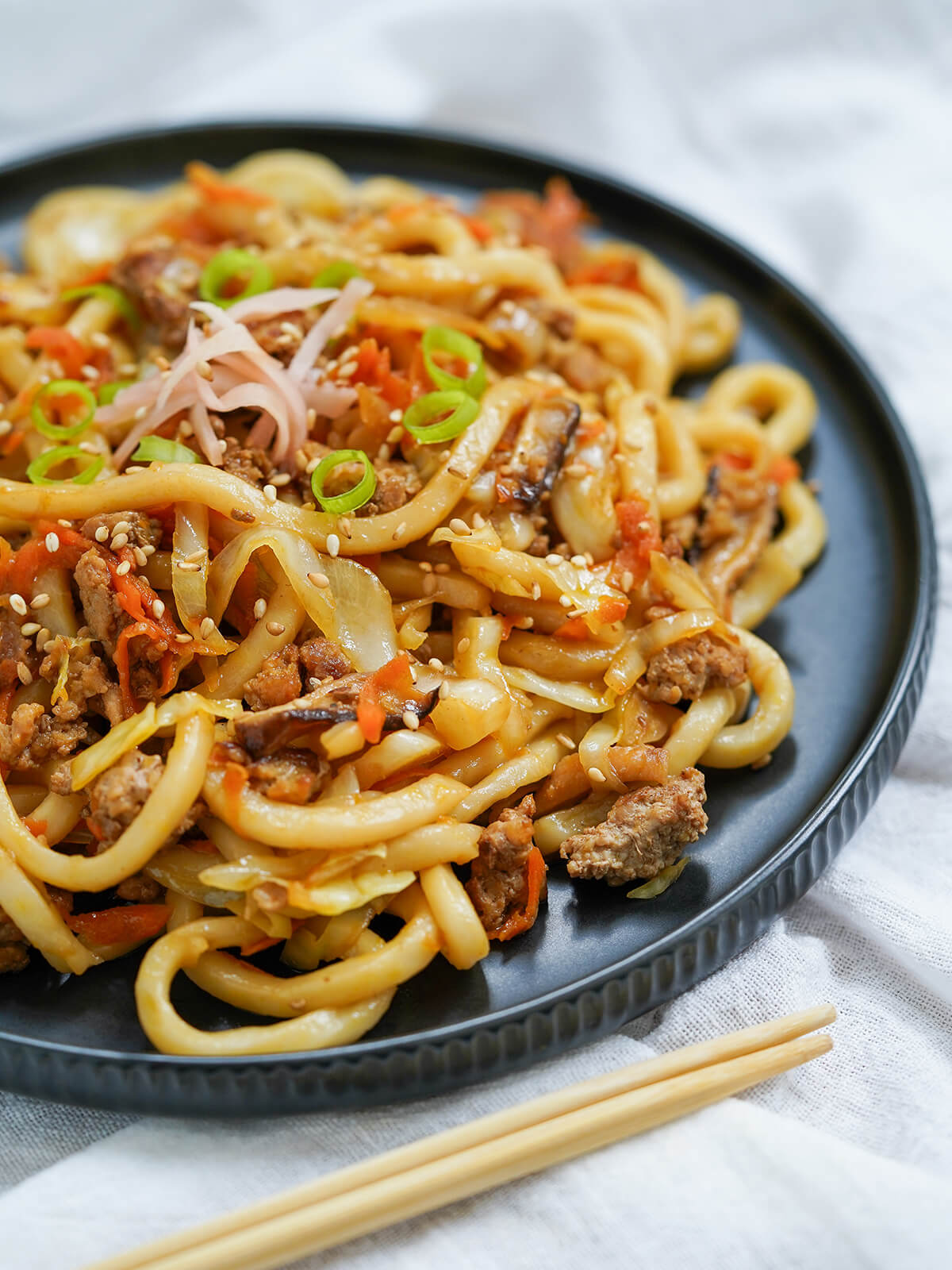 side view of plate of yaki udon with ends of chopsticks in front.