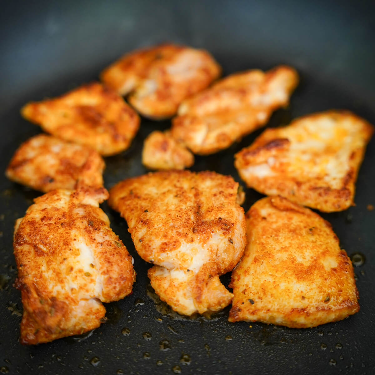 cooking chicken with taco seasoning on it in skillet.