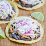 side view of chicken tostadas with wedge of lime between.