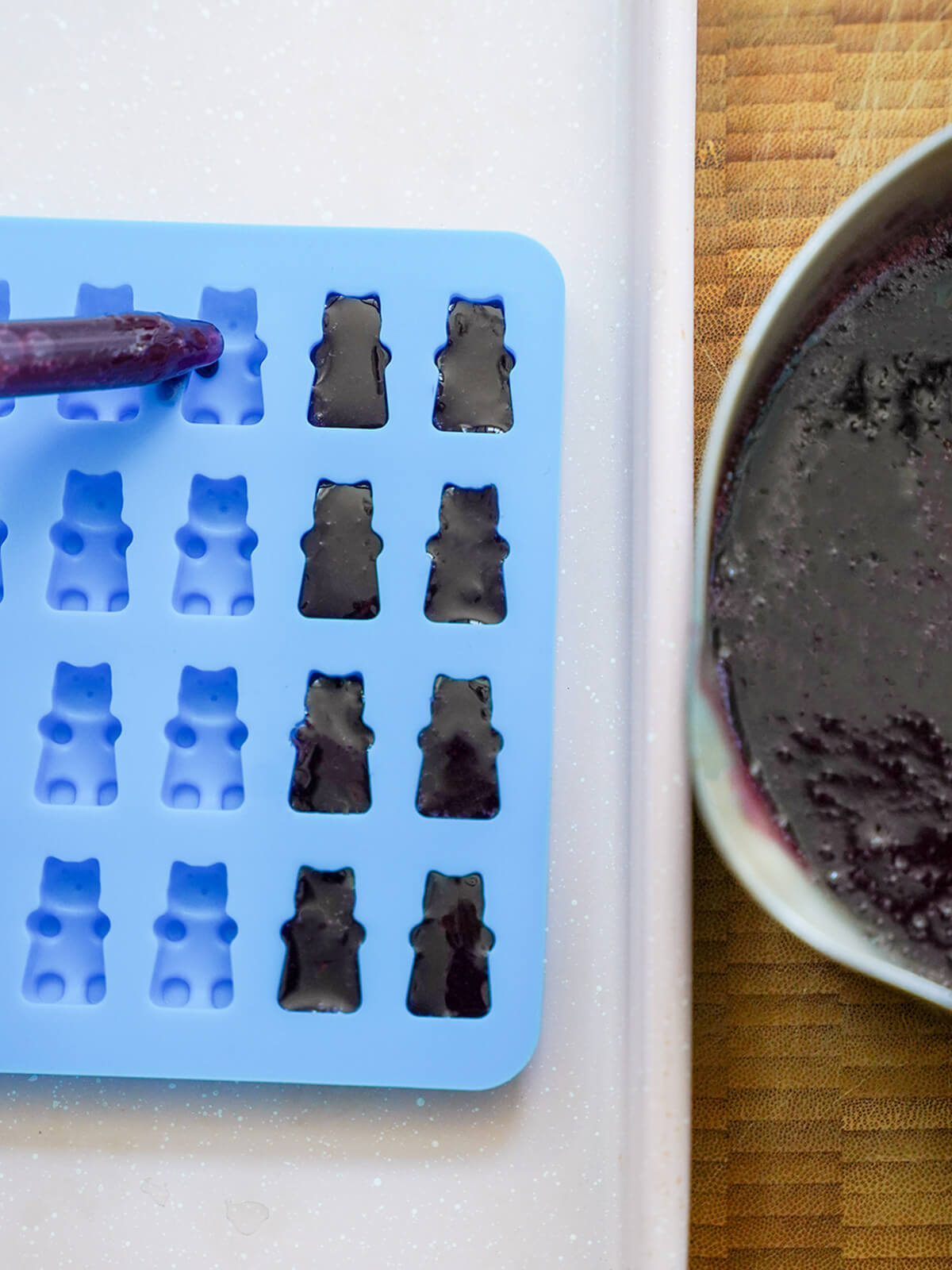 filling moulds for grape gummy bears using dropper to fill bear shaped moulds with jelly liquid.