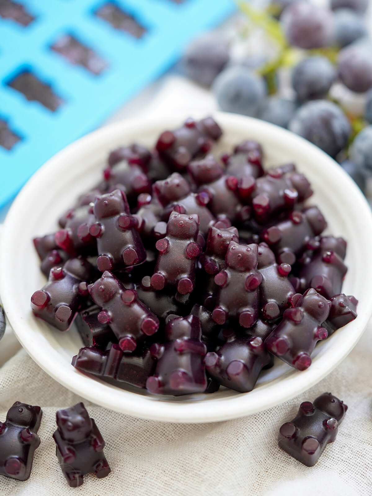 homemade grape gummy bears are easy to make, fun and tasty little bites. close shot of dish of grape gummy bears with a couple in front.