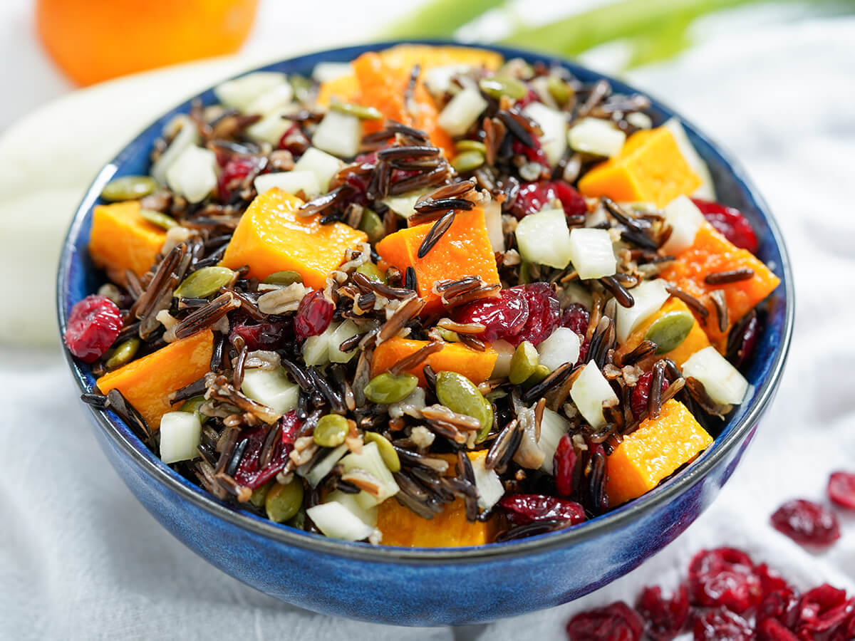 close side view of blue bowl filled with butternut squash wild rice salad.