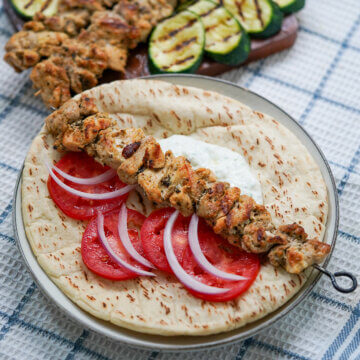 grilled chicken souvlaki on top of pita with tzatziki, tomato and red onion
