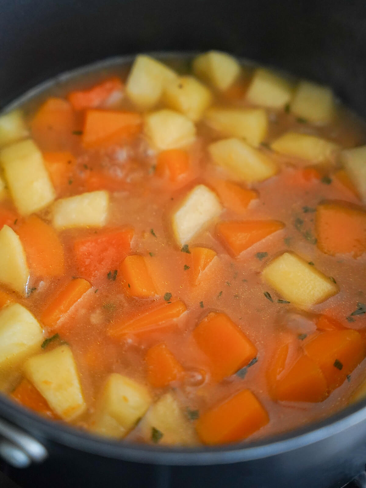 chunks of squash and apple in pot with stock.