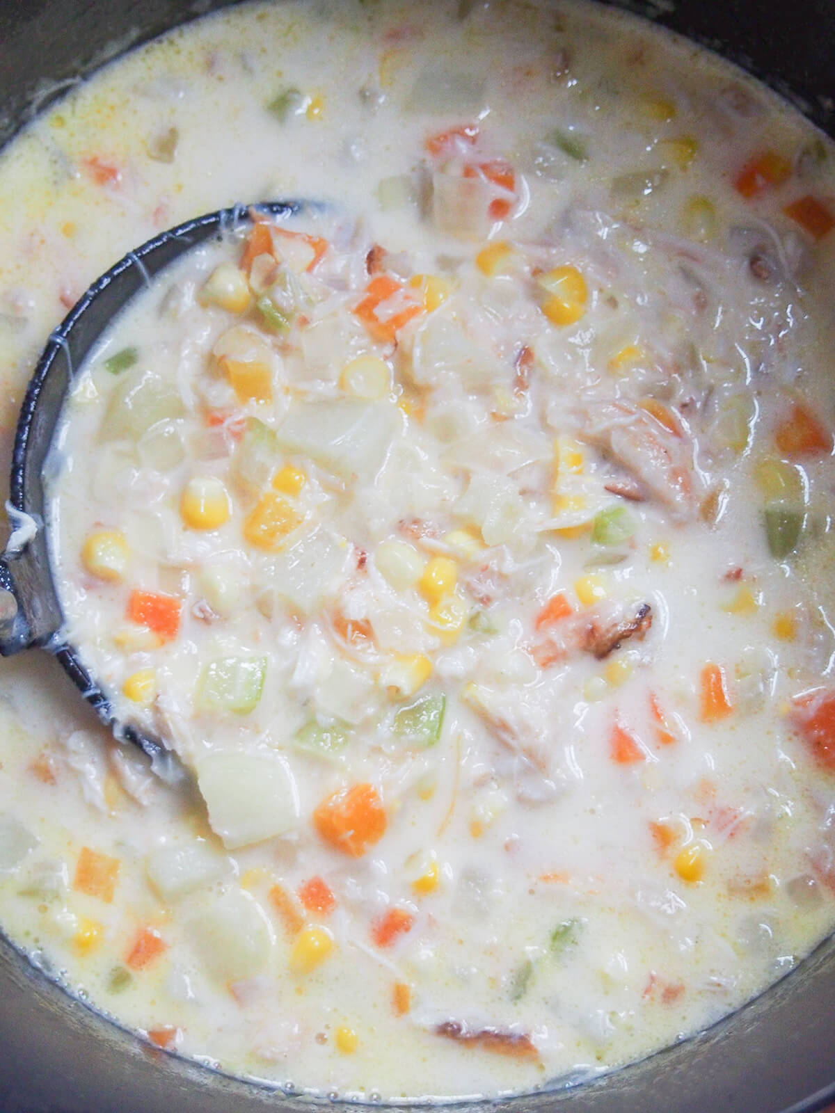 This crab and corn chowder is a delicious combination of flavors that's hearty, comforting and filling yet feels that bit lighter and indulgent with the crab and corn. Perfect for any occasion. ladle inside pot of crab and corn chowder with lots of chunks of vegetable and crab in it.