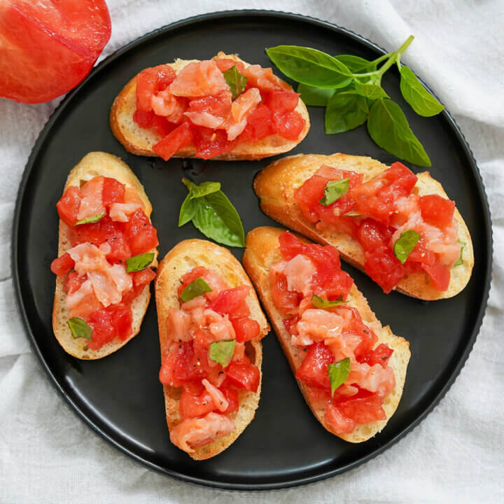 overhead view of a plate of smoked salmon bruschetta with basil garnish on plate.