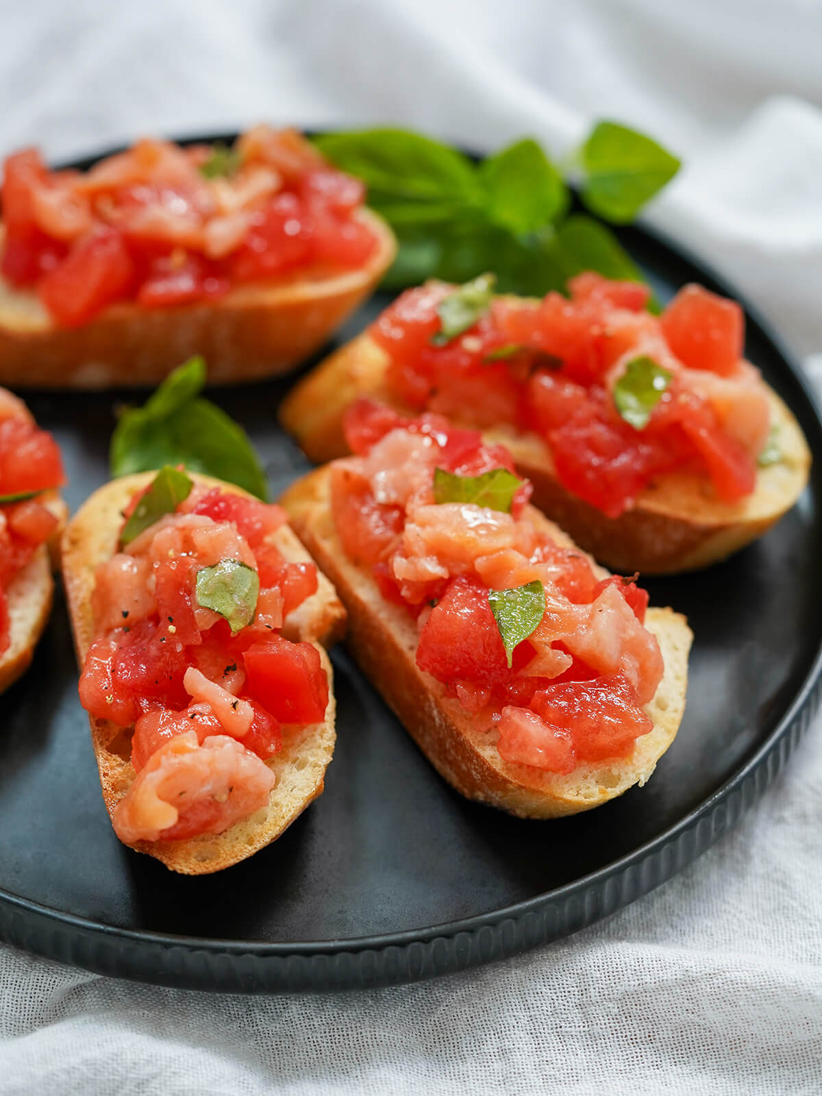 A light and delicious appetizer, this smoked salmon bruschetta is a simple twist on a classic. It's great for any occasion and quick to prepare. pieces of smoked salmon bruschetta on plate.