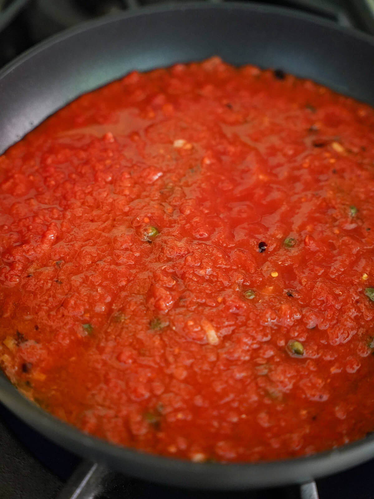 tomato, caper, anchovy and garlic sauce simmering in skillet.