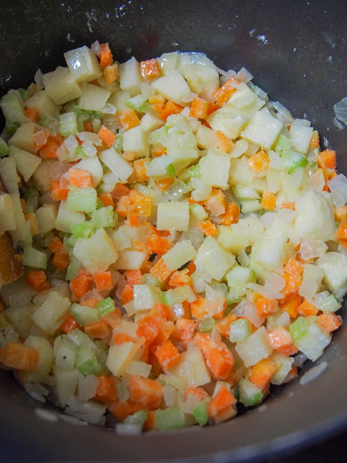 cooking vegetable base for crab and corn chowder part cooked diced potato, carrot, onion and celery in pot with flour added giving slight coating.