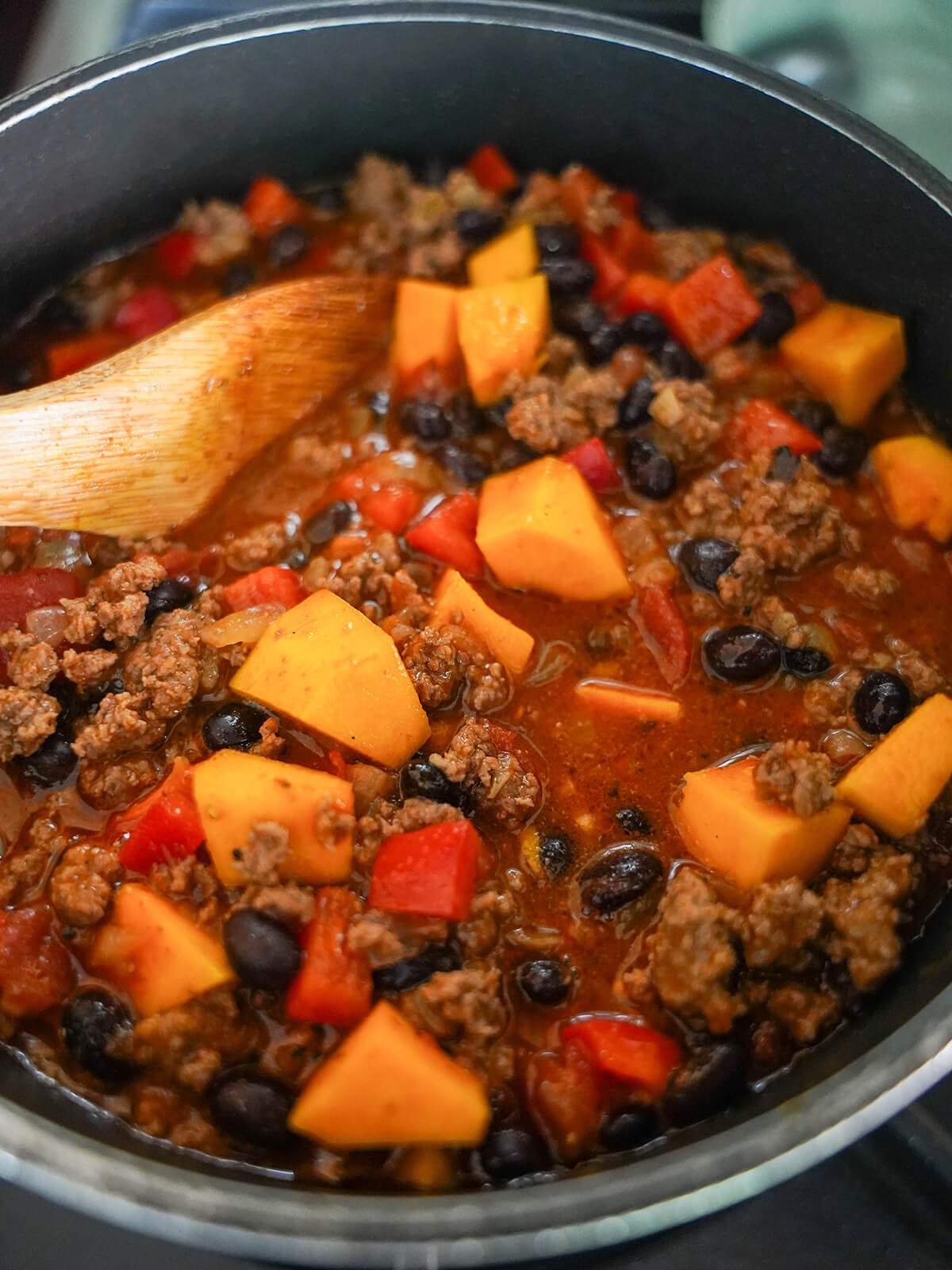 cooking chili with butternut squash in pot.