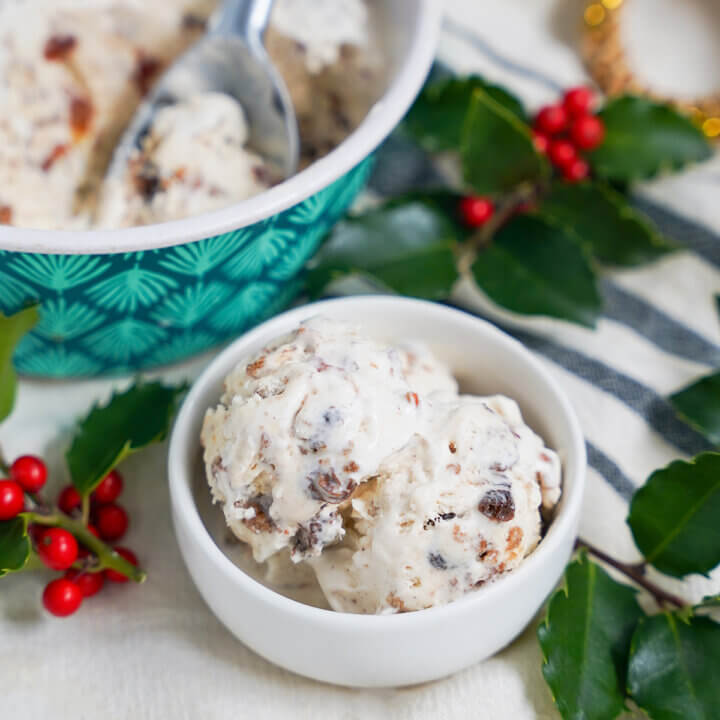 Christmas pudding ice cream in small dish with holly behind.