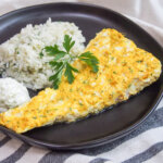 Persian style marinated fish on plate with herbed rice behind and parsley garnish.