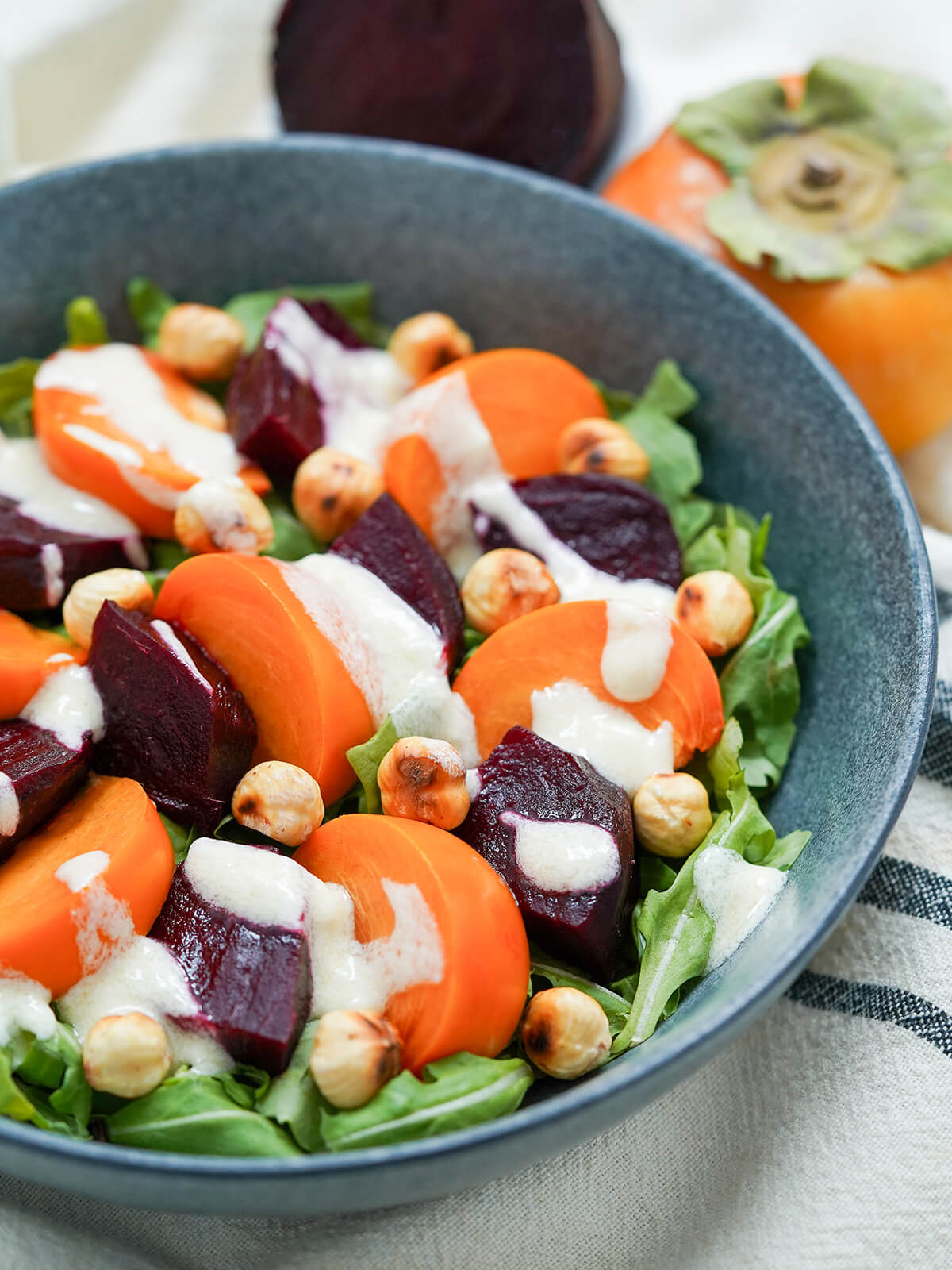 beet persimmon salad with goat cheese dressing side view of part of bowl of beet persimmon salad.