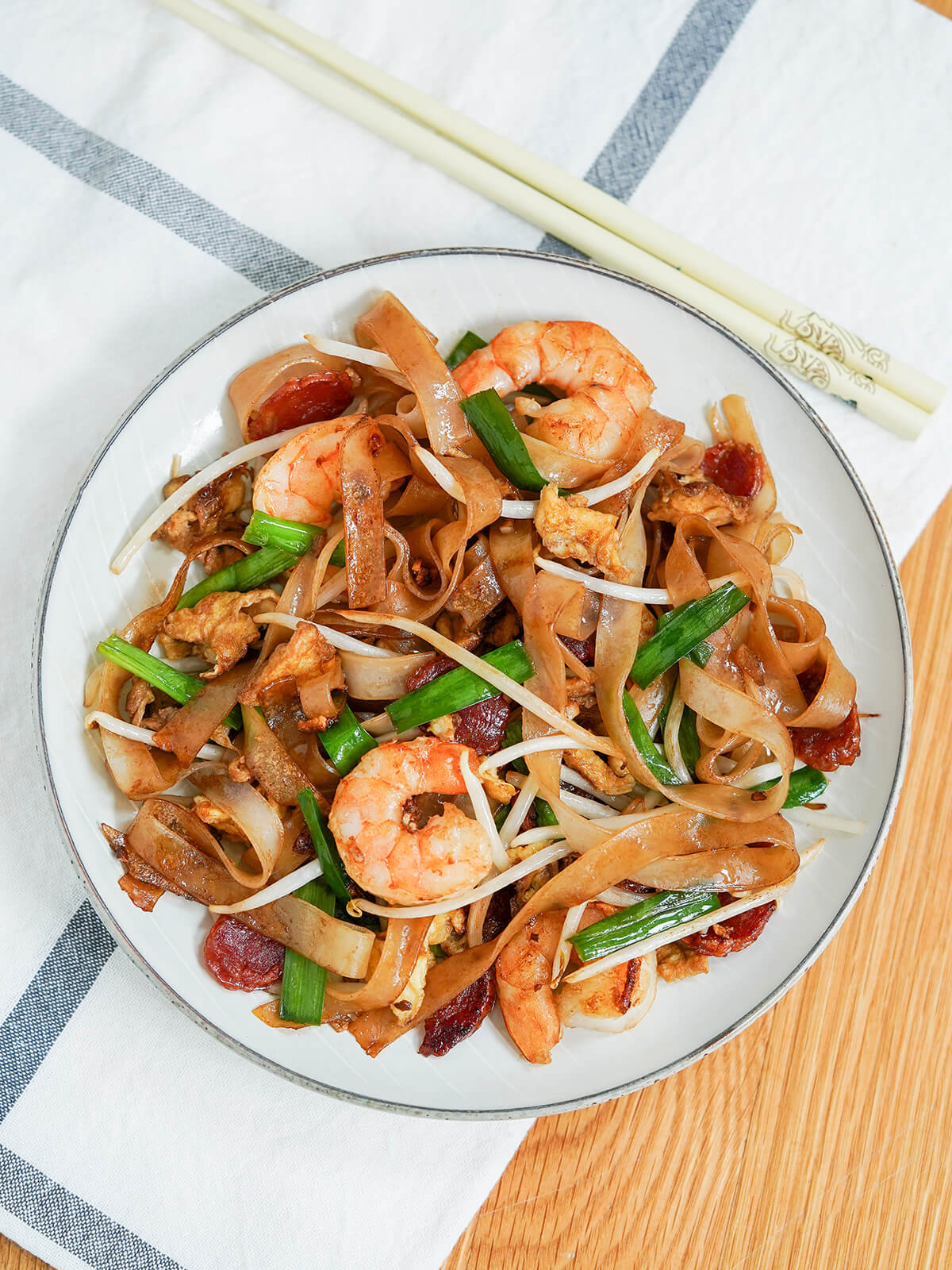 overhead pic of char kway teow with chopsticks on cloth above plate.